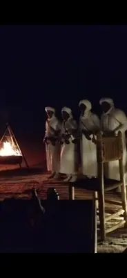 a group of birds sitting on a table next to a fire at LUNA LLENA Desert Camp Merzouga in Merzouga