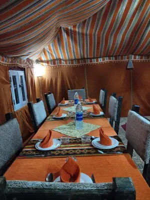a dining room with a long table with plates of food at LUNA LLENA Desert Camp Merzouga in Merzouga