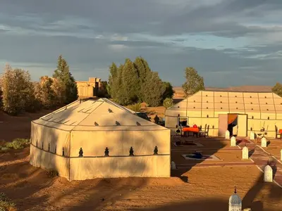 a large white building with a roof in the desert at LUNA LLENA Desert Camp Merzouga in Merzouga