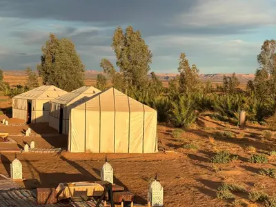 a group of tents in the middle of a field at LUNA LLENA Desert Camp Merzouga in Merzouga