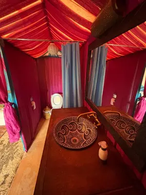 a room with a bed and a table in a tent at LUNA LLENA Desert Camp Merzouga in Merzouga