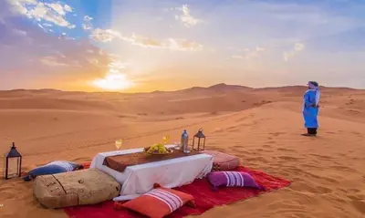 a man standing in the desert with a table in the desert at Gite Omar merzouga in Merzouga