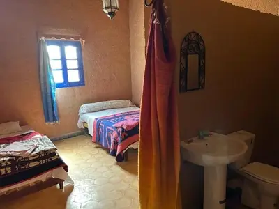 a bathroom with a sink and a toilet and a bed at Gite Omar merzouga in Merzouga