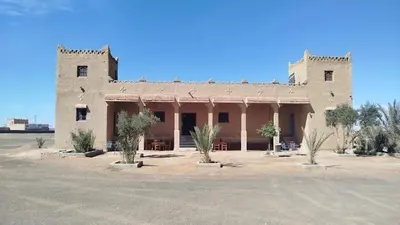 a large building with trees in front of it at Gite Omar merzouga in Merzouga