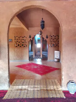 a large room with a red rug and an archway at Gite Omar merzouga in Merzouga