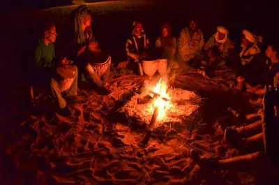 a group of people sitting around a fire at Gite Omar merzouga in Merzouga