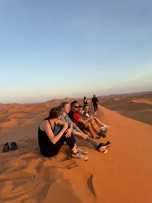 a group of people sitting on top of a sand dune at Ksar merzouga luxury camp in Merzouga