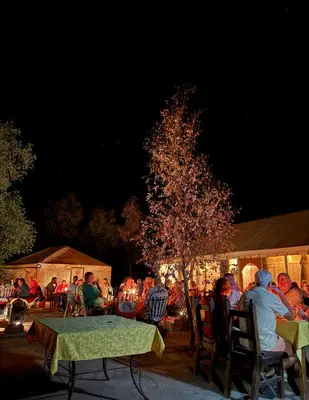 a group of people sitting around a table at night at Ksar merzouga luxury camp in Merzouga