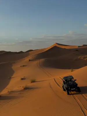 a jeep parked in the sand in the desert at Ksar merzouga luxury camp in Merzouga