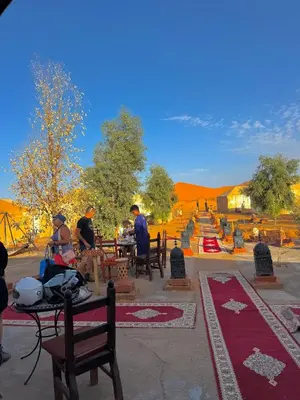 a group of people sitting at tables in the desert at Ksar merzouga luxury camp in Merzouga
