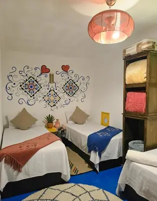 a room with two beds and a chandelier at Riad Dalia - Fes Medina in Fès