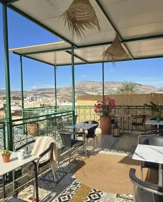 a patio with tables and chairs and mountains in the background at Riad Dalia - Fes Medina in Fès