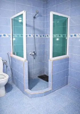 a blue tiled bathroom with a shower and a toilet at Riad Dar Babouche in Fès