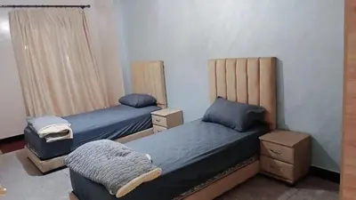 a bedroom with two beds and a chair in it at séjour à MARRAKECH in Oulad Akkou