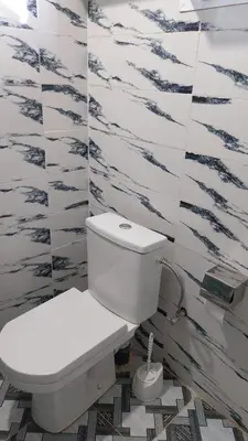 a white toilet in a bathroom with black and white tiles at Berber Family