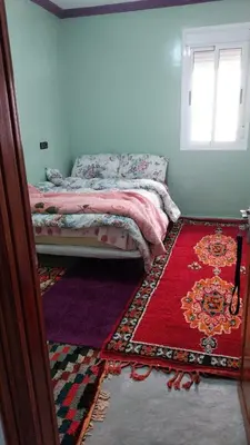 a bedroom with a bed with a red rug and a window at Berber Family