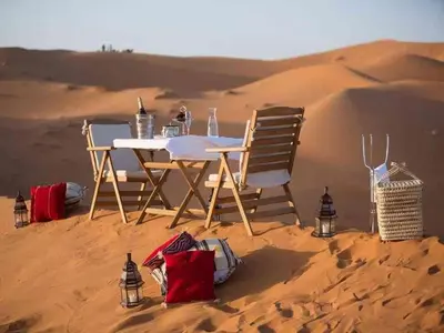 a table and chairs in the sand in the desert at Maps of dreams camp in Merzouga