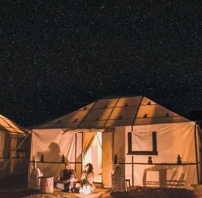 two people sitting in a tent under a night sky at Morocco luxury Camp in Merzouga