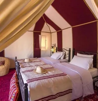 a bedroom with two beds with hats on them at Morocco luxury Camp in Merzouga
