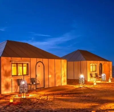 two domed buildings with lights on them at night at Morocco luxury Camp in Merzouga