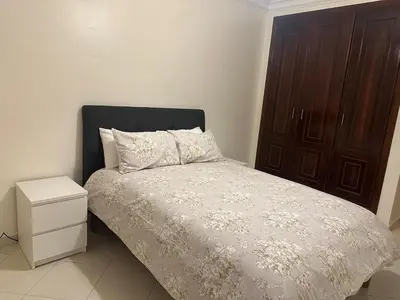 a bedroom with a bed and a wooden cabinet at 3 bedroom stunning flat Central Tanger Ville - Iberia in Oulad Akkou