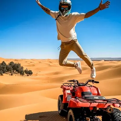 a man jumping over a quad bike in the desert at Sahara Moon Luxury Camp in Merzouga