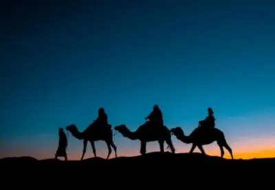 a group of people riding on camels in the desert at Sahara Moon Luxury Camp in Merzouga