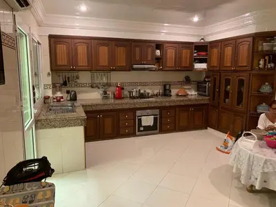 a kitchen with wooden cabinets and a woman sitting at a table at Tessas Crib in Fès