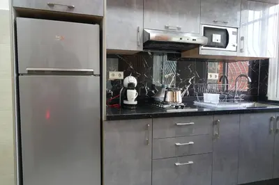 a kitchen with a stainless steel refrigerator and a microwave at APPARTEMENT AMJAD iFRANE in Ifrane