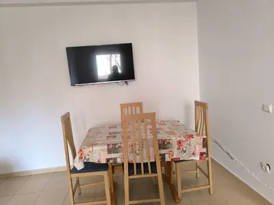 a dining room table with chairs and a television on a wall at Le séjour agréable in Ifrane
