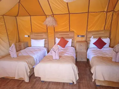 a group of three beds in a tent at Dune's treasure, luxury camp in Merzouga