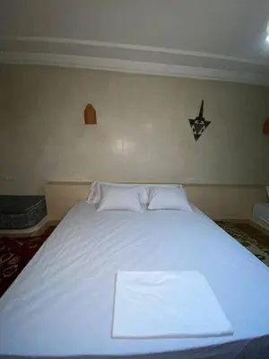 a white bed with two pillows and a star on the wall at Auberge Soleil Bleu in Boumalne