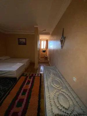 a bedroom with two beds and a rug on the floor at Auberge Soleil Bleu in Boumalne