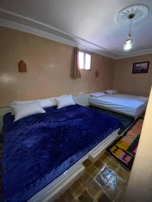 two beds in a bedroom with a blue blanket at Auberge Soleil Bleu in Boumalne