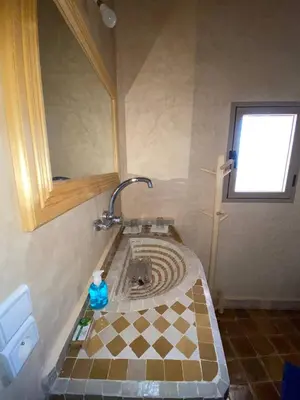 a bathroom with a sink with a cross and a mirror at Auberge Soleil Bleu in Boumalne