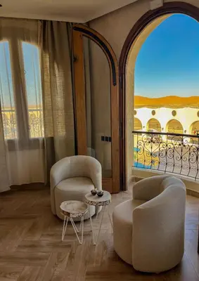 a living room with two chairs and a large window at Nasser Palace Suites & Spa in Hassilabied