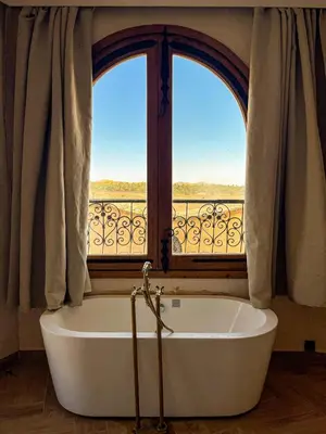 a bath tub in a room with two windows at Nasser Palace Suites & Spa in Hassilabied