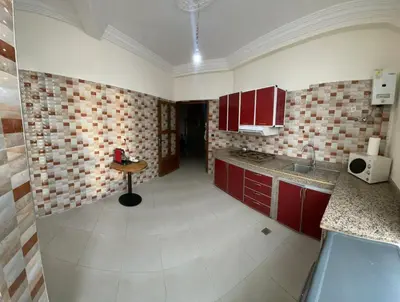 a kitchen with red cabinets and a table in it at appartement chic, calme et bien équipé in Meknès