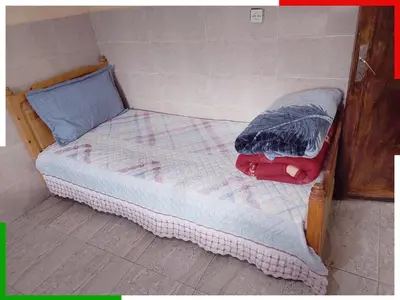 a small bed with a wooden frame in a room at Appartement familial en sous-sol près des chutes d'Ouzoud, confortable et sûr in Azilal
