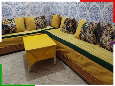 a couch with a yellow table in a room at Appartement familial en sous-sol près des chutes d'Ouzoud, confortable et sûr in Azilal