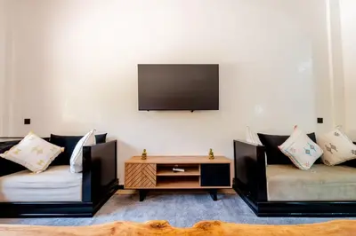 a living room with two couches and a tv on the wall at Charming Flat with AC Fast Wifi Secure Residence in Oulad Akkou