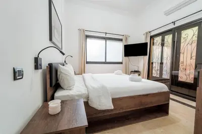 a bedroom with a bed with white sheets and a table at Charming Flat with AC Fast Wifi Secure Residence in Oulad Akkou