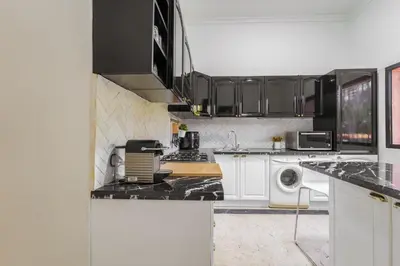 a kitchen with white cabinets and black counter tops at Charming Flat with AC Fast Wifi Secure Residence in Oulad Akkou