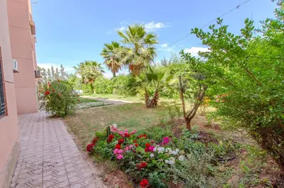 a garden with flowers and palm trees and a sidewalk at Charming Flat with AC Fast Wifi Secure Residence in Oulad Akkou