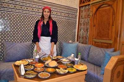 a woman standing in front of a table of food at Riad Dar Salma in Fès