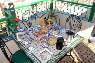 a table with food on it on a balcony at Riad Dar Salma in Fès