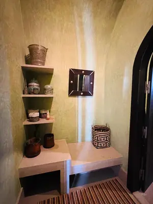 a room with a table and shelves with baskets on the wall at Villa Fatima, Route de Fès in Oulad Akkou
