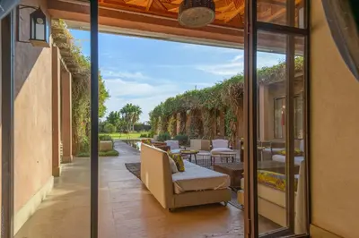 an outdoor patio with chairs and tables and sliding glass doors at Villa Fatima, Route de Fès in Oulad Akkou