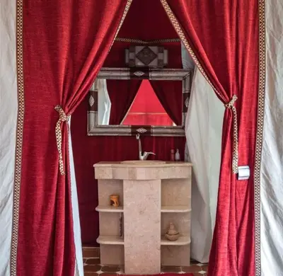 a bathroom with red curtains and a sink and a mirror at Merzouga Boho Camp in Merzouga