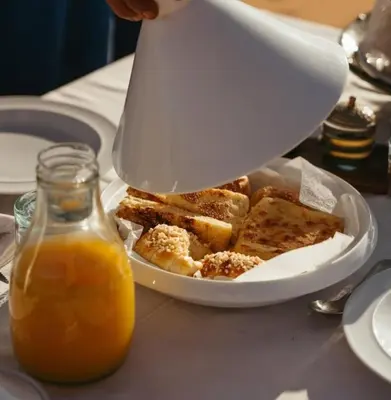 a plate of toast and a pitcher of orange juice at Merzouga Boho Camp in Merzouga